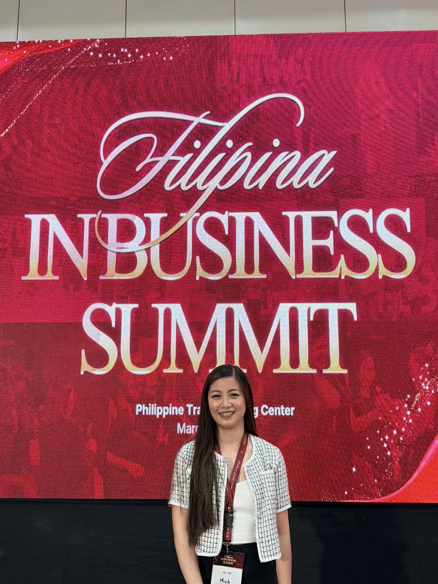 Mitch Ramos at the Filipina In Business Summit, standing before the event backdrop